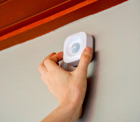 A technician installs a modern movement detector in a cozy apartment