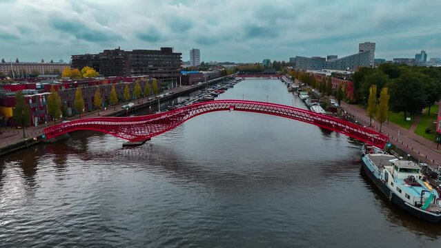 Aerial drone view of modern footbridge Python Bridge at Eastern Docklands neighborhood of Amsterdam Netherlands. High quality 4k footage
