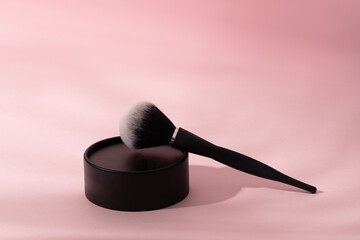 Loose powder box and black brush on pink background with shadow, modern make up advertising of cosmetic product - 778687502