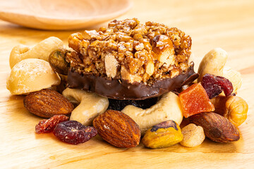 Closeup view of peanuts, almond and chocolate mini protein bars on pile of mixed fruits and nuts...