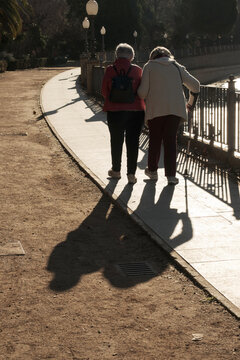 Pareja de ancianas pasenado por el parque, anciana con bastón agarrada por su cuidadodra, vejez, cuidados, demencia, salud