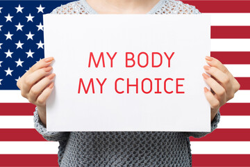 woman holding poster my body is my choice on american flag background,advocating for reproductive...