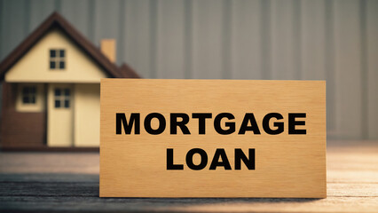 Mortgage Loan Concept: Wooden Sign with Blurred House Model Background