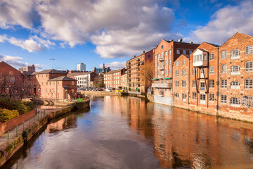 Leeds, West Yorkshire, England, UK - the River Aire in the centre of the city, with apartment buildings on either side, some converted warehouses, some new builds, all reflecting in the water.