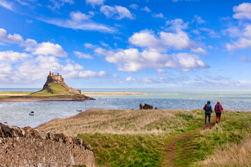 Lindisfarne - Hikers walking on the Lindisfarne Heugh, Holy Island, Northumberland,  UK, on a sunny spring day.