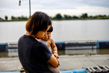 Mother and son watching fish in a pond of a fish farm.