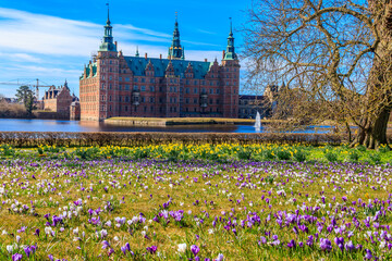 View of Frederiksborg castle in Hillerod, Denmark. Beautiful lake and garden with crocuses and...