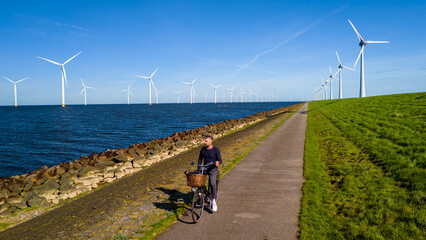 A man gracefully rides a bike along a path next to a tranquil body of water in the scenic landscape...