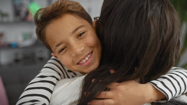 A smiling boy embraces a woman in a cozy indoor setting, portraying warmth and family connection.