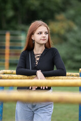 Portrait of a young beautiful red-haired girl in a summer park.