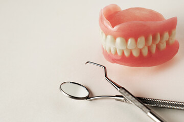 Dentures and dentist tools on a white background with copy space