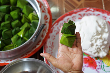 Hand show wrapped dough with green banana leaf  for cooking Thai traditional dessert. Concept, Thai food. How to cook, step of cooking. Thai traditional lifestyle, Prepare food for culture celebration