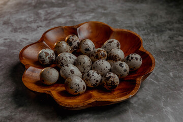 Wooden plate with quail eggs on a gray background
