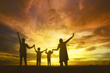Silhouette of Muslim family holding hands together at sunrise or sunset