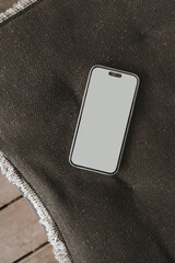 Mobile phone with blank screen on black pillow. Flat lay, top view template with copy space