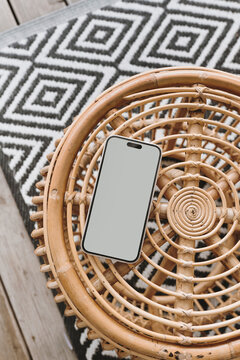 Fototapeta Mobile phone with blank screen on ornamental wooden table and carpet. Flat lay, top view template with copy space