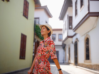 female summer travel to Antalya, Turkey. young asian woman in red dress walk through old town Kalechi , female tourist traveler discover interesting places and popular tourist attraction