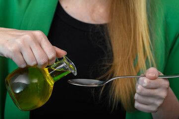 Kobieta pije olej, nalewać olej na łyżeczkę  - obrazy, fototapety, plakaty