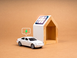 Sustainability at home concept. Solar panels being installed on the roof of white modern house near white EV car toy with electric power icon in speech bubble on recycle paper background.