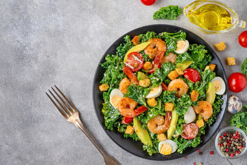 Delicious seafood salad with shrimps, kale cabbage, avocado, tomatoes and quail eggsin a plate with fork on gray concrete background. Top view with copy space. Healthy diet food for dinner - 778776390