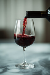 Pouring a rich red wine into an elegant glass on a marble surface.
