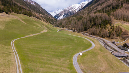Aerial drone view of an alpine meadow during early spring time. some dirt roads are in the meadow....