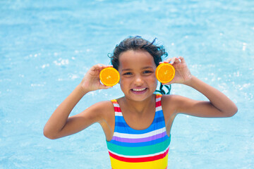 Child with orange in swimming pool