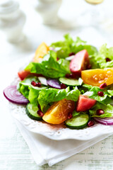 Salad with red and yellow Tomatoes and Pomegranate Seeds on bright wooden Background. Close up.