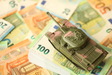 Obraz na płótnie Canvas Many euro banknotes and tank. Lot of bills of European union currency and green tank close up
