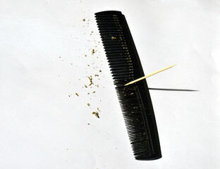 Picking and scraping off with a wooden tooth pick hair grease crumbs from between teeth of a black...