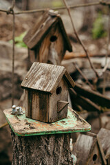 An old gray wooden birdhouse against the background of another birdhouse