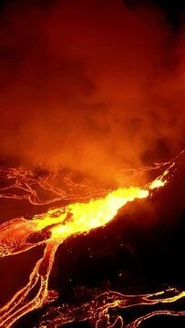 Ash clouds and lava rivers expelled from active volcano at night