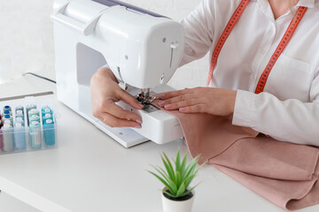A pattern, scissors, a centimeter tape and a sewing machine. The seamstresses workplace.