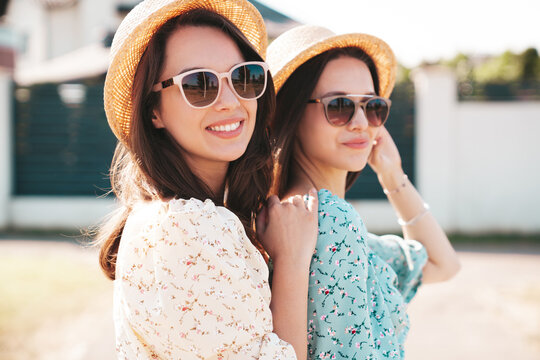Two young beautiful smiling hipster female in trendy summer dresses  clothes. Sexy carefree women posing in the street. Positive models having fun at sunny day. Going crazy. In sunglasses