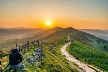 Landscape photographer at Mam Tor hill  in Peak District taking picture at sunrise - Powered by Adobe