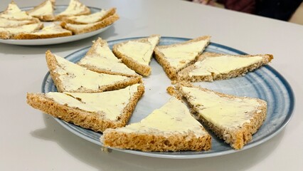 Two gray plates with toasted bread cut in half and buttered. Side view. Snack. Kitchen