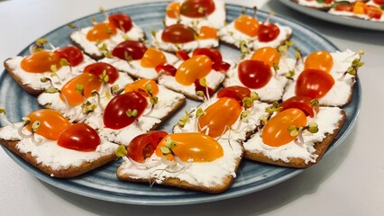Close crackers spread with soft cottage cheese with cherry tomatoes cut in half and decorated with...