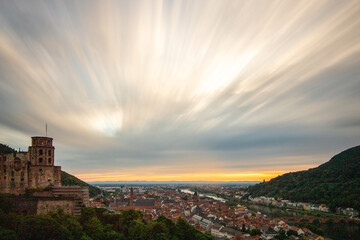 Fototapeta na wymiar View over an old town with a castle or palace rune in the evening at sunset. This place is located in a river valley of the Neckar, surrounded by hills. Heidelberg, Baden-Württemberg, Germany