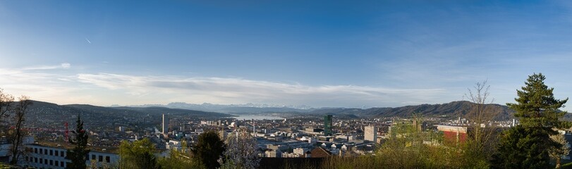 Fototapeta na wymiar Large panorama of the city of Zurich in spring with the snowy Swiss Alps in the background from the Waid