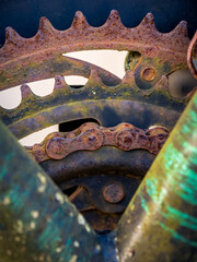 A detailed close-up reveals rusted front chainrings and a corroded bicycle chain, framed by a weathered bicycle frame in dire need of replacement, showcasing the worn components of a dilapidated bike. - obrazy, fototapety, plakaty