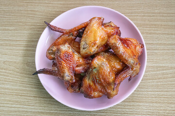 Thai food - Grilled Chicken Wings on plate. Chicken wings marinated in sweet sauce Thai people like to eat it with papaya salad and fresh vegetables.