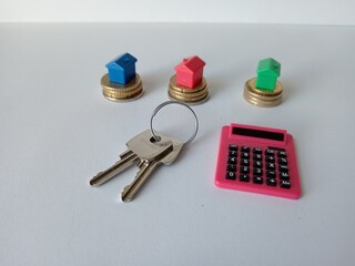 small colored houses on coins with keys calculator on a white background