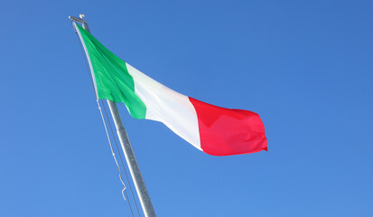 Italian flag with green white and red colors waving in the cloudless sky