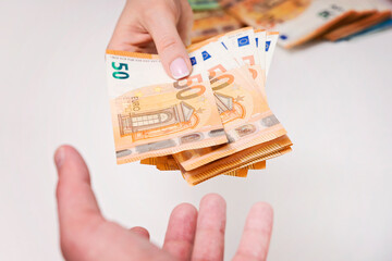 Human hand holding a bunch of Euros banknotes. Man giving money to a woman. Street economy,...