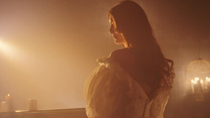 Woman in vintage dress looking away in a candlelit room with fog. Period drama concept with copy space for design and print. Cinematic portrait with atmospheric lighting.