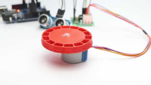 Stepper motor with 3D printed attachment on its shaft making movement when obstacle is detected by ultrasonic sensor for electronics prototyping