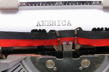 Typewritten AMERICA in black ink on white paper with an antique typewriter