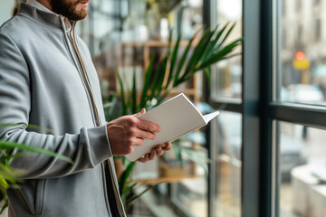 businessman in a business suit reads a magazine near the window with a plant