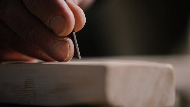Nails in the cross of Jesus Christ, Carpenter places first nail into a wooden cross, and hammered into the wood. Passion of Christ, hand-made cross sequence.
