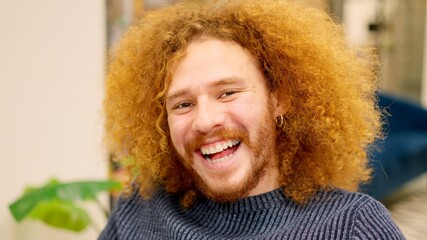 Man with curly hair smiling at camera in a coworking